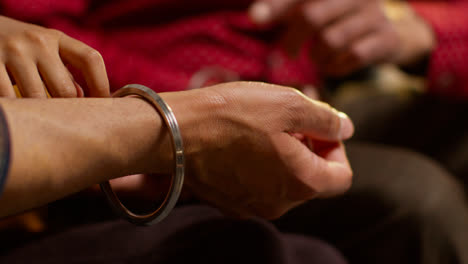 Close-Up-Of-Multi-Generation-Male-Sikh-Family-Wearing-And-Discussing-Traditional-Silver-Bangles-Or-Bracelets-Sitting-On-Sofa-At-Home-1